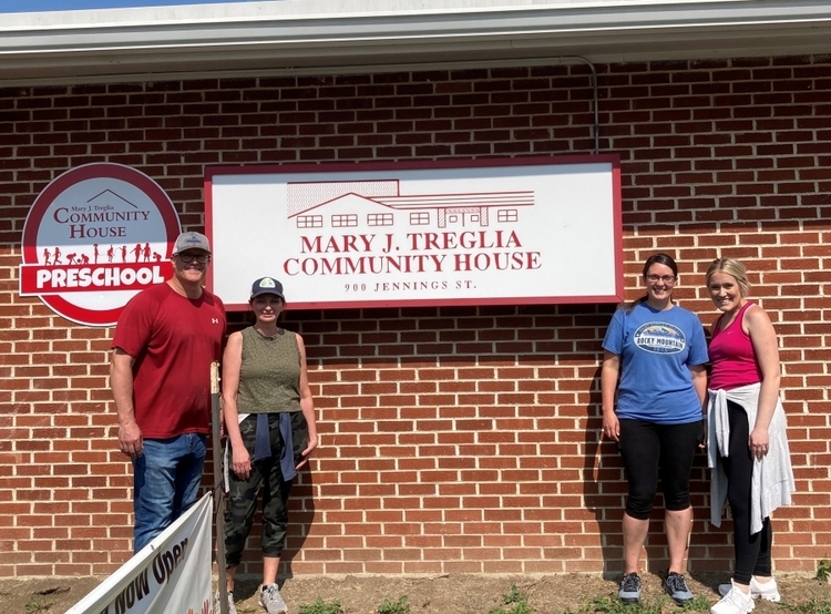Four volunteers standing outside community house preschool building
